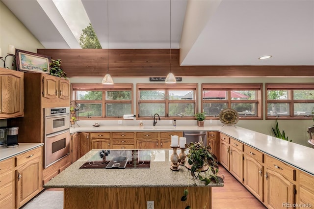 kitchen featuring pendant lighting, appliances with stainless steel finishes, a kitchen island, a sink, and light wood-type flooring