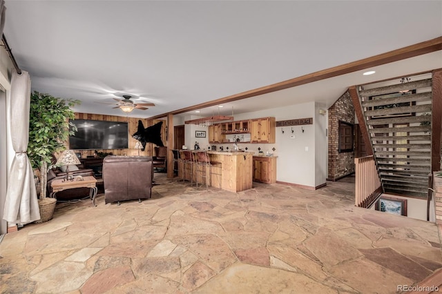 living room with wet bar, stone flooring, and ceiling fan