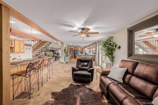 living room with ceiling fan, stairs, and stone finish flooring