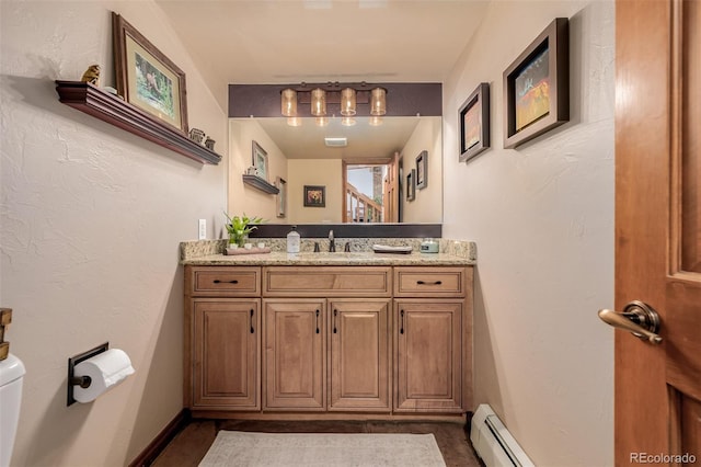 bathroom featuring baseboards, a textured wall, vanity, and toilet