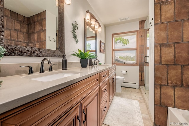 bathroom with a baseboard heating unit, a sink, a shower stall, and double vanity