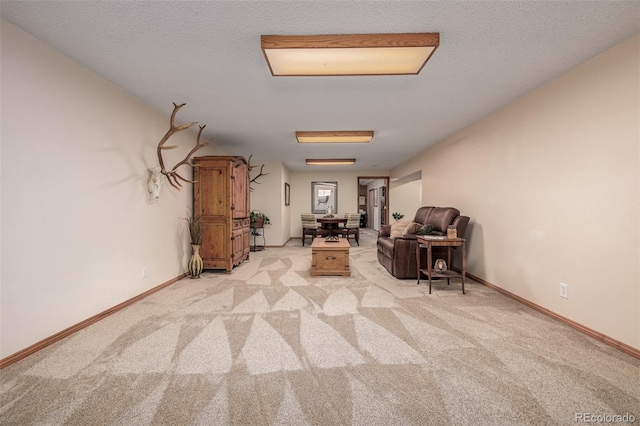 interior space featuring light colored carpet, a textured ceiling, and baseboards