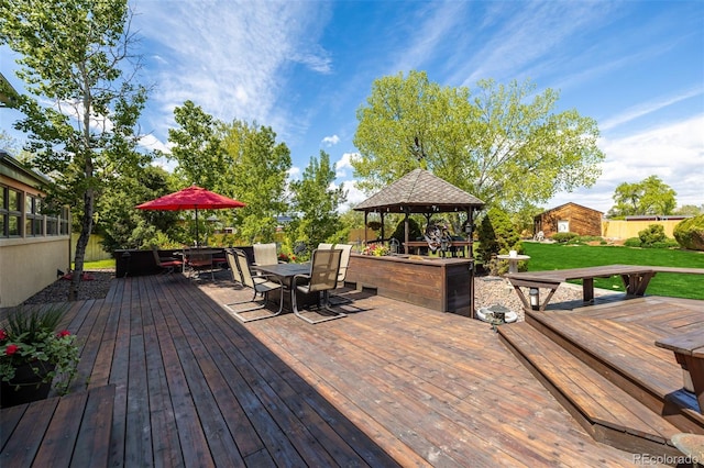 wooden terrace featuring outdoor dining space, a lawn, and a gazebo