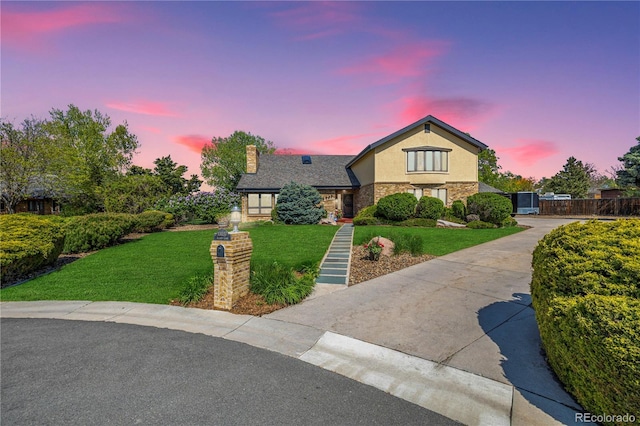 view of front of home with stone siding, a chimney, fence, a front lawn, and stucco siding