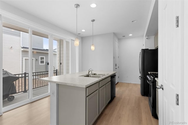 kitchen with light wood finished floors, light countertops, gray cabinetry, a sink, and black appliances