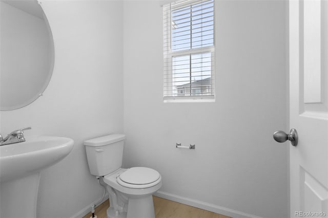 bathroom with toilet, baseboards, a sink, and wood finished floors