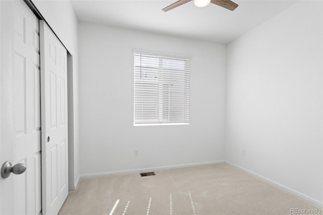 unfurnished bedroom featuring carpet floors, a closet, visible vents, a ceiling fan, and baseboards