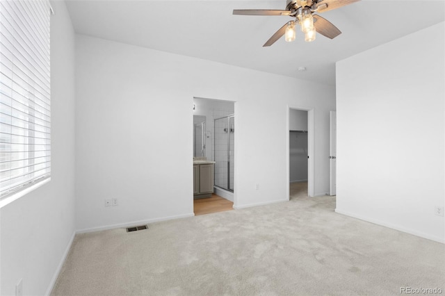 unfurnished bedroom featuring baseboards, a spacious closet, visible vents, and light colored carpet