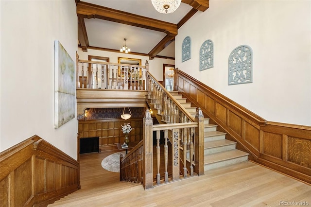 stairway with beamed ceiling, a chandelier, and hardwood / wood-style floors