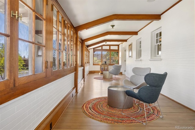 sitting room featuring hardwood / wood-style floors, lofted ceiling with beams, and brick wall