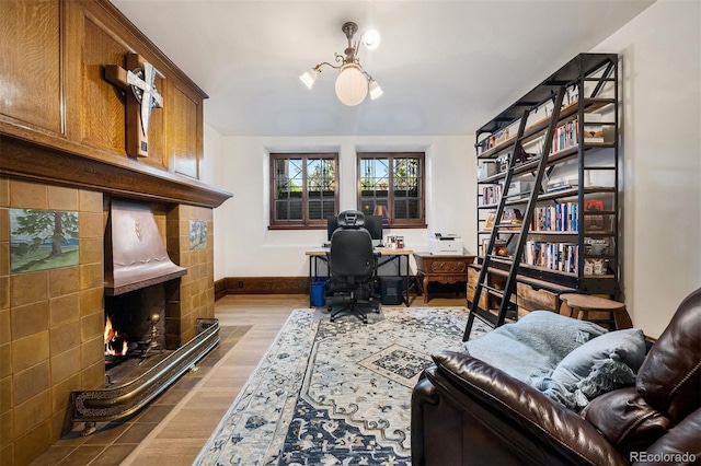 office space with a tiled fireplace and light hardwood / wood-style floors