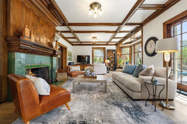 living room with coffered ceiling, a wealth of natural light, a premium fireplace, and light hardwood / wood-style flooring