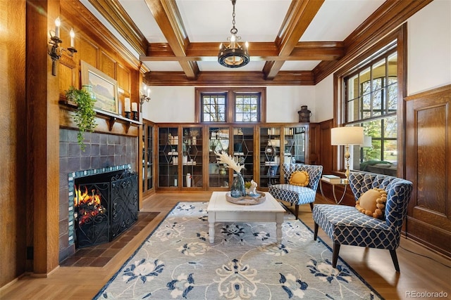 living room with beamed ceiling, a tiled fireplace, coffered ceiling, and crown molding