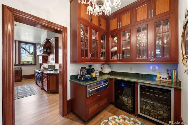 bar with premium range hood, light wood-type flooring, beverage cooler, and high end range