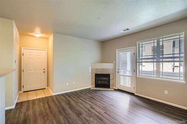 unfurnished living room with baseboards, a fireplace, wood finished floors, and visible vents