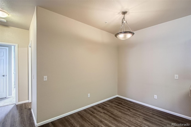 empty room with baseboards and dark wood-style floors