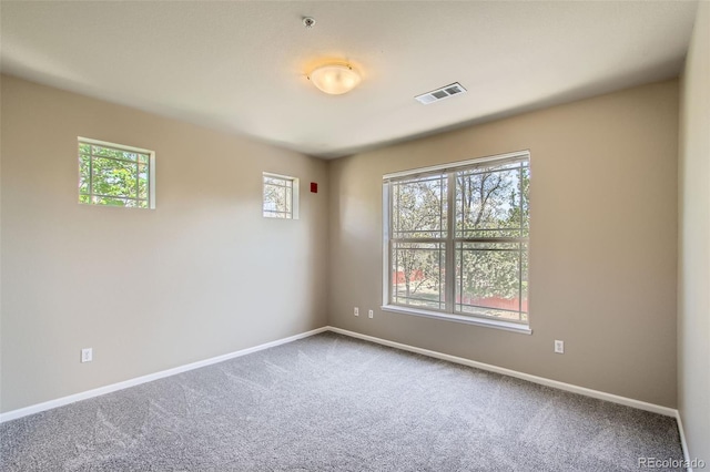 spare room with baseboards, carpet flooring, and visible vents