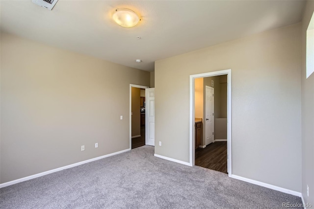 unfurnished bedroom featuring baseboards, visible vents, and dark carpet