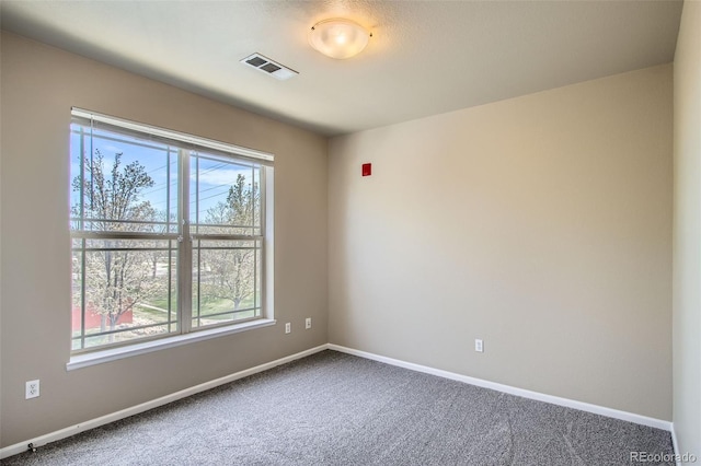 carpeted spare room with visible vents, baseboards, and a wealth of natural light