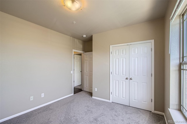 unfurnished bedroom featuring carpet floors, baseboards, and a closet