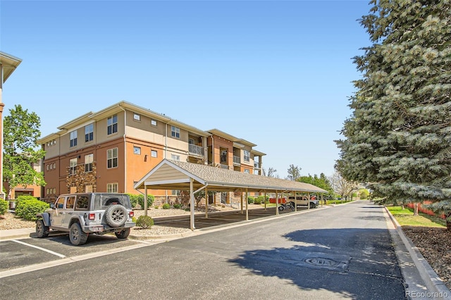 view of building exterior featuring covered and uncovered parking