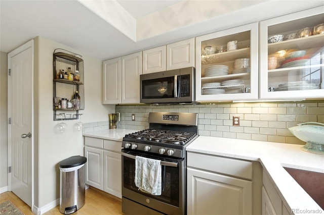 911 Laramie Blvd Unit B, Boulder, CO 80304 - kitchen with appliances with stainless steel finishes, light wood-style floors, light countertops, glass insert cabinets, and backsplash