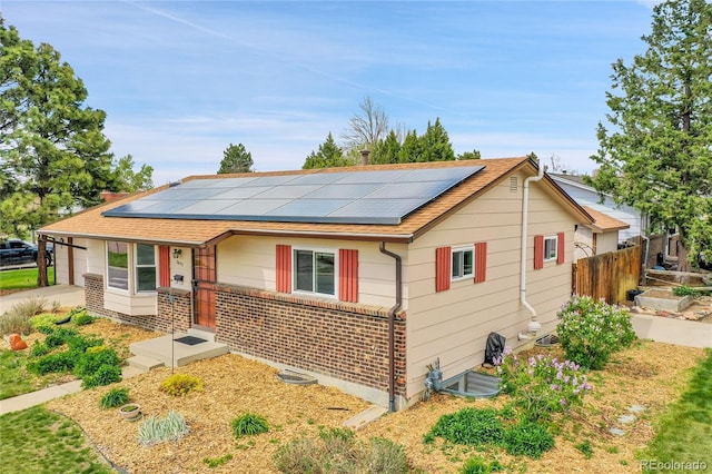 3451 Highland Pl, Westminster, CO 80031 - view of front of property featuring roof mounted solar panels, fence, driveway, and brick siding