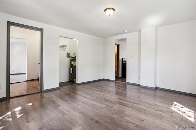 unfurnished room featuring hardwood / wood-style floors and electric water heater