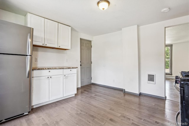 kitchen featuring stainless steel fridge, white cabinetry, range with gas stovetop, and light wood-type flooring