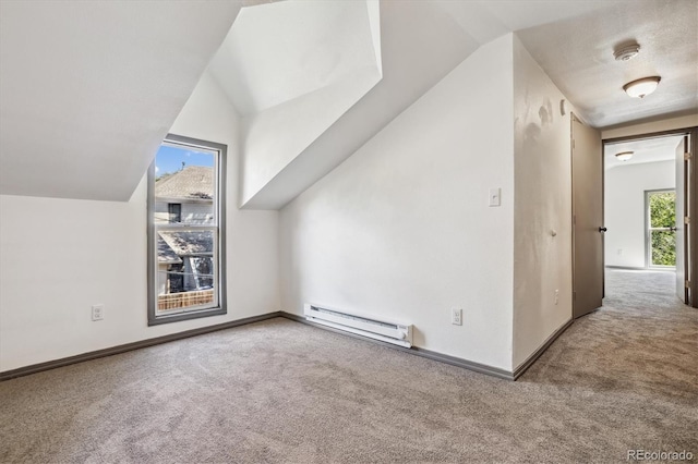 additional living space with a baseboard radiator, vaulted ceiling, and light carpet