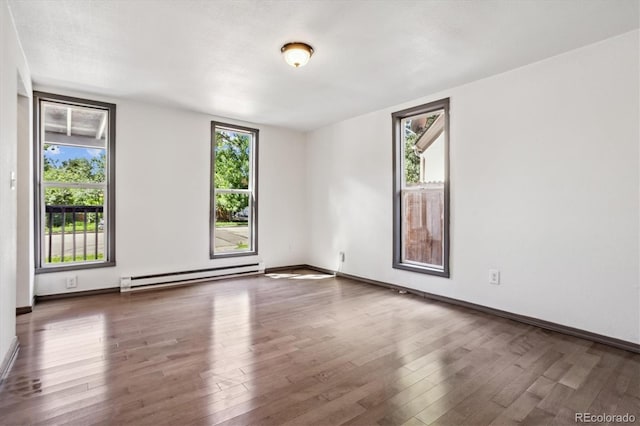 unfurnished room with a baseboard radiator, a wealth of natural light, and wood-type flooring