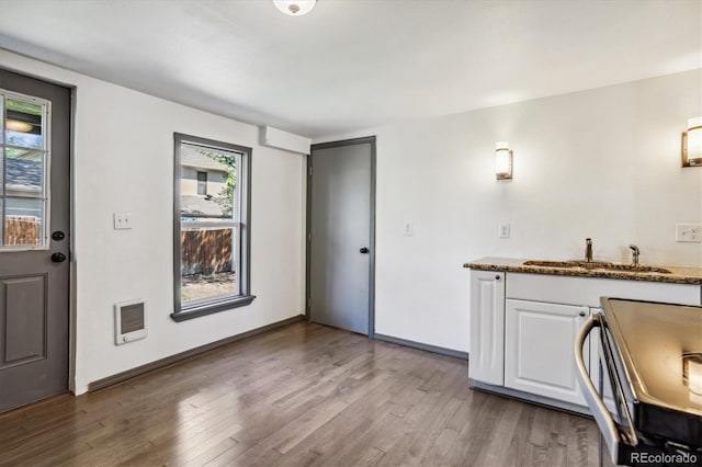 interior space with white cabinets, hardwood / wood-style flooring, stone counters, sink, and stove