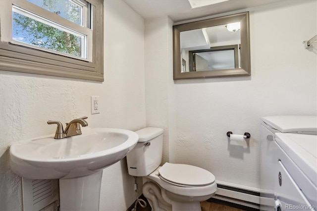 bathroom featuring toilet, separate washer and dryer, wood-type flooring, and a baseboard radiator