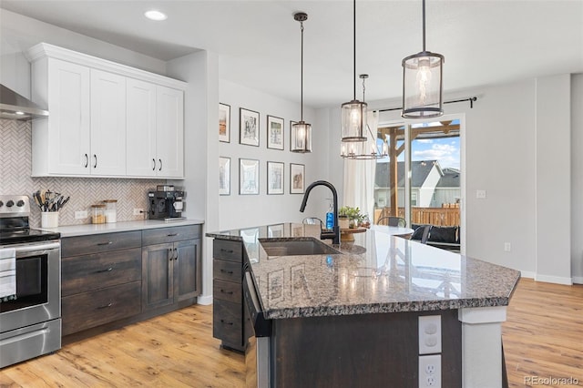 kitchen with electric range, white cabinets, decorative backsplash, light wood-type flooring, and a sink