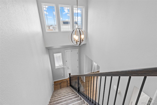 staircase with carpet floors and a chandelier