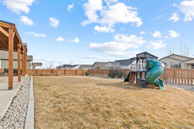 view of yard featuring a playground, a fenced backyard, and a residential view