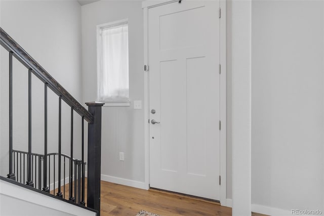 foyer entrance featuring stairway, baseboards, and wood finished floors