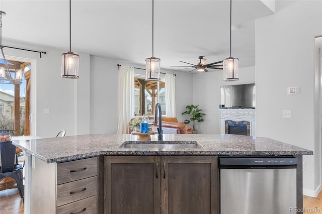 kitchen featuring light wood-style floors, open floor plan, a sink, light stone countertops, and dishwasher