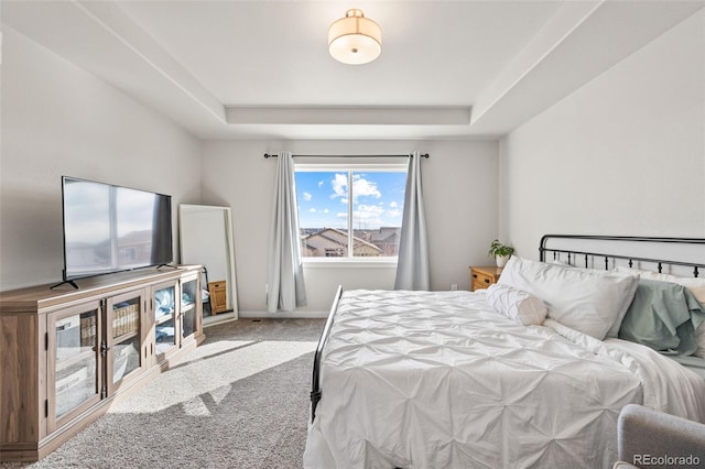 carpeted bedroom with a raised ceiling and baseboards