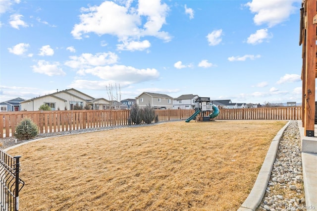 view of yard with a playground, a fenced backyard, and a residential view