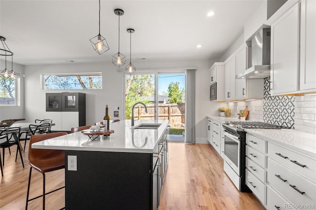 5240 N Raleigh St, Denver, CO 80212 - kitchen with gas range, a sink, wall chimney range hood, light countertops, and an island with sink