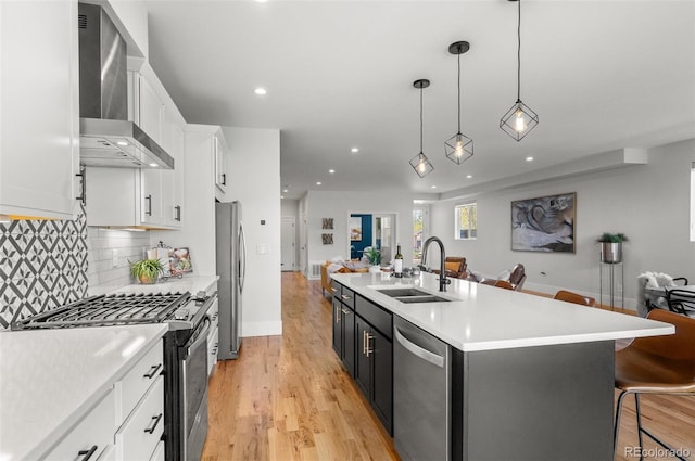 5240 N Raleigh St, Denver, CO 80212 - kitchen featuring appliances with stainless steel finishes, a sink, wall chimney range hood, open floor plan, and white cabinetry