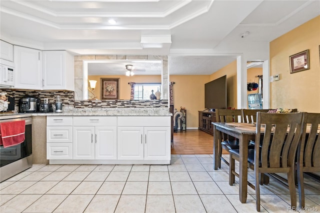 kitchen with light stone countertops, stainless steel range with electric cooktop, light tile patterned floors, tasteful backsplash, and white cabinets