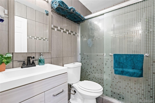 bathroom with toilet, decorative backsplash, tile walls, a shower with door, and vanity