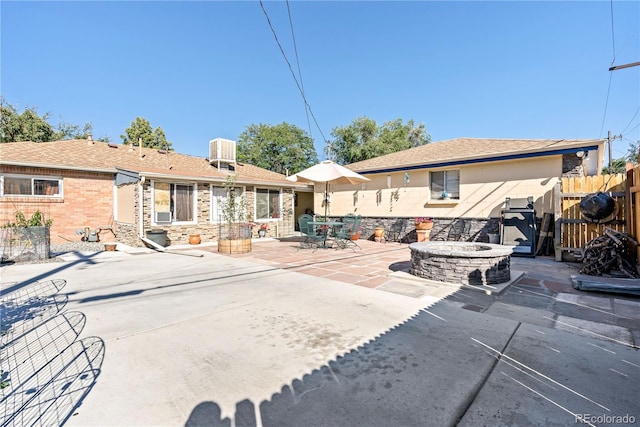 rear view of property featuring an outdoor fire pit and a patio