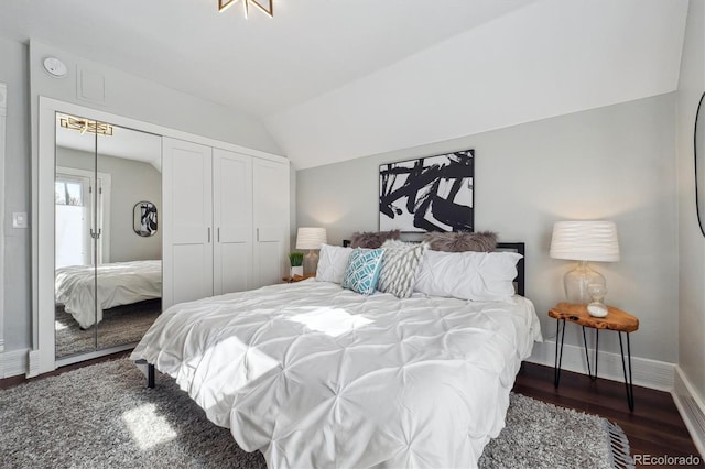 bedroom with lofted ceiling, dark wood-style floors, baseboards, and a closet