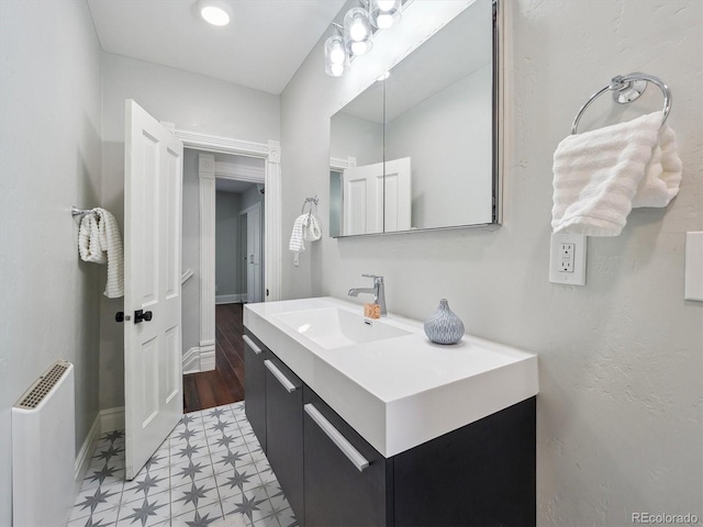 bathroom with radiator, baseboards, and vanity