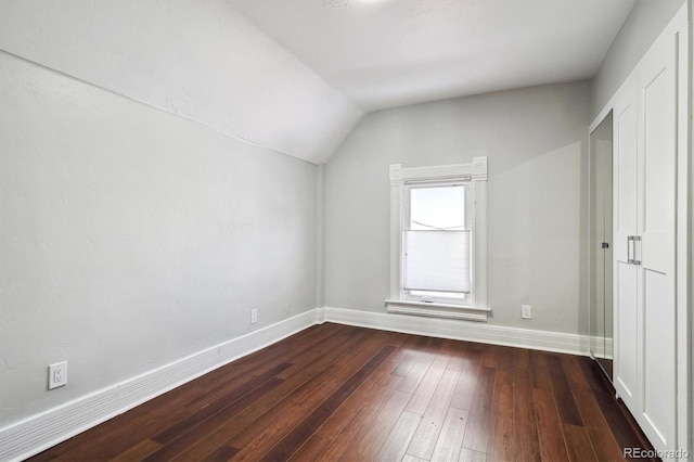 additional living space with dark wood-style flooring, vaulted ceiling, and baseboards