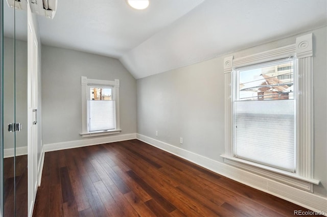 interior space with dark wood-style floors, baseboards, vaulted ceiling, and a wealth of natural light