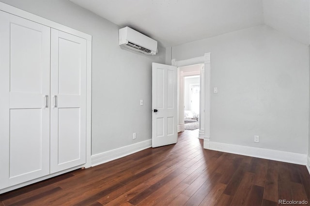 unfurnished bedroom with dark wood-type flooring, a closet, baseboards, and a wall mounted AC